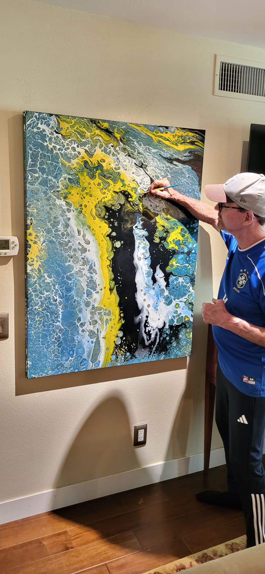 Mike adding detail to a large blue, yellow, black and white abstract painting